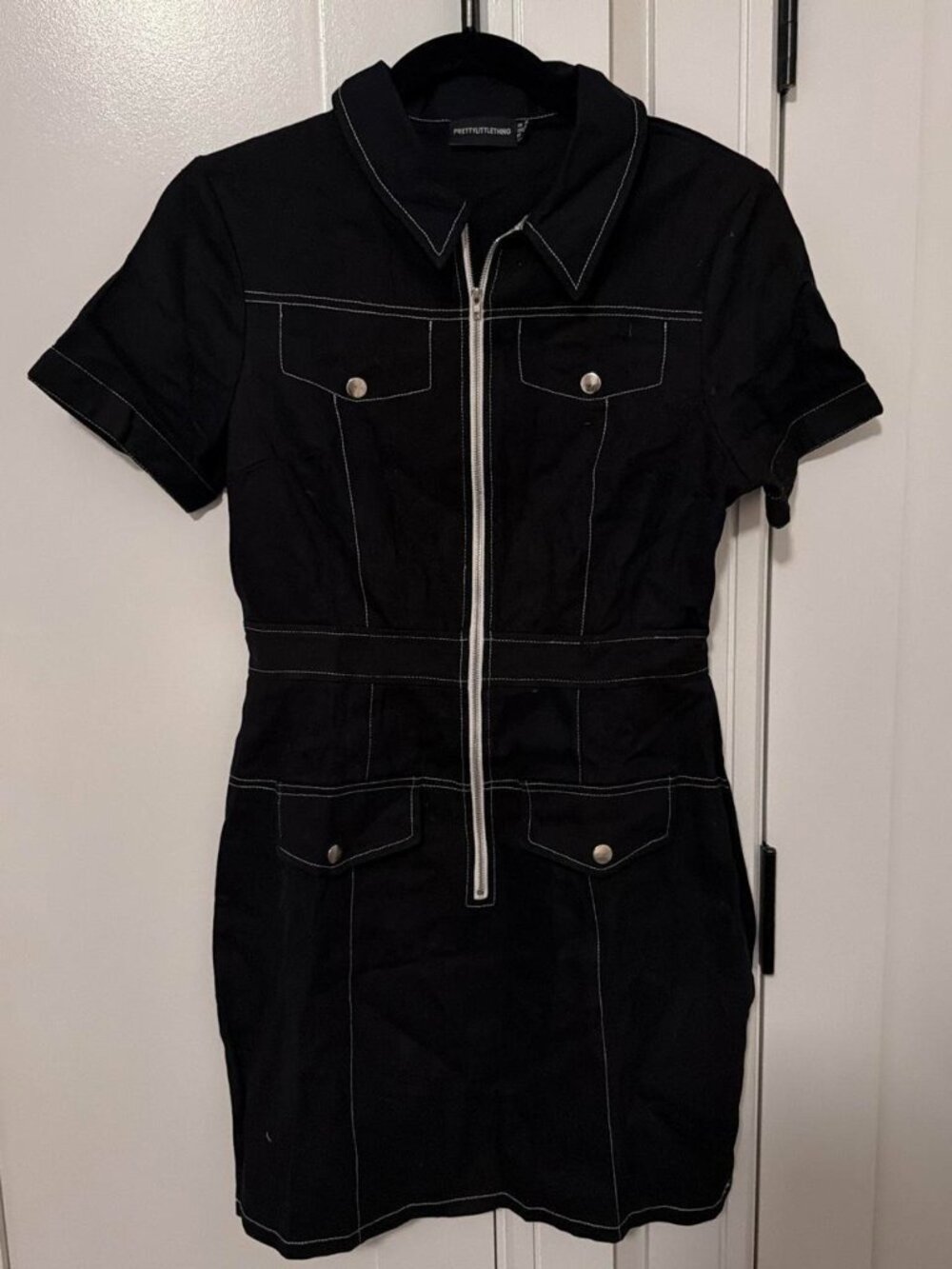 Black denim mini dress with white stitching and faux pockets